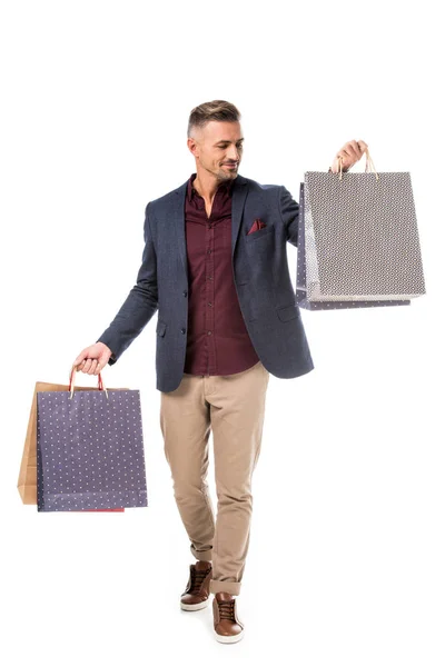 Comprador masculino feliz en chaqueta caminando con coloridas bolsas de papel aisladas en blanco - foto de stock