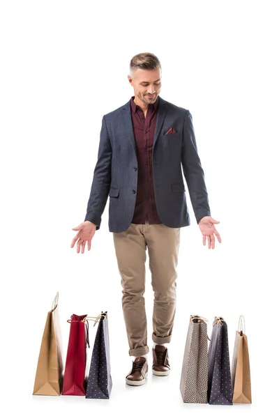 Stilvoller Mann in Jacke zeigt auf bunte Einkaufstüten auf weißem Grund — Stockfoto