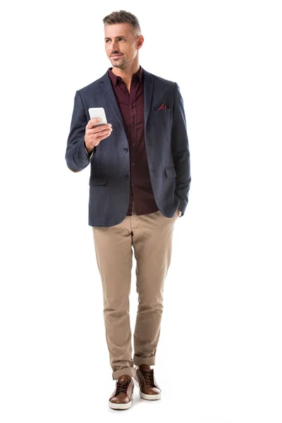 Homme élégant en veste à l'aide d'un smartphone et regardant loin isolé sur blanc — Photo de stock