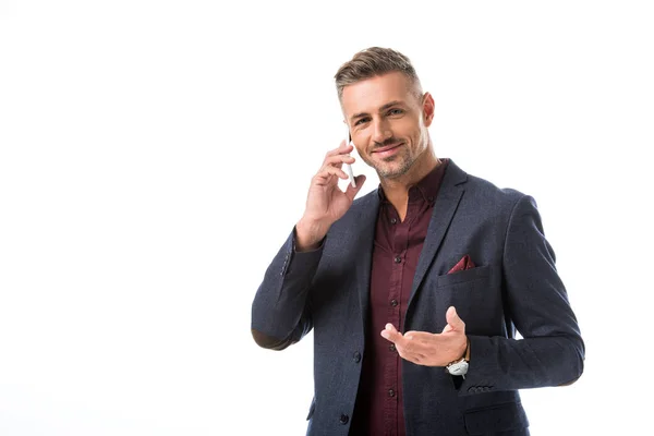 Gioioso uomo elegante gesticolando a mano mentre parla su smartphone isolato su bianco — Foto stock