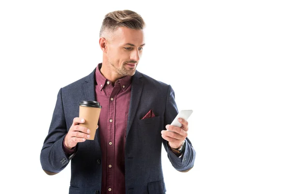 Homem elegante bonito com xícara de café usando smartphone isolado no branco — Fotografia de Stock