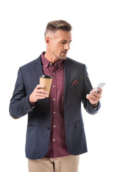 Homem elegante emocional com copo de café descartável usando smartphone isolado no branco — Fotografia de Stock