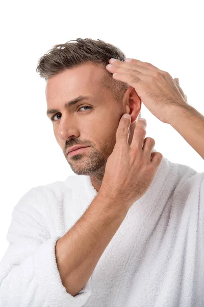 Hombre adulto molesto en albornoz comprobándose a sí mismo para la pérdida de cabello aislado en blanco - foto de stock