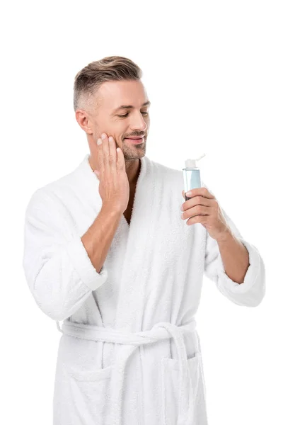 Happy handsome adult man in bathrobe using shaving lotion isolated on white — Stock Photo