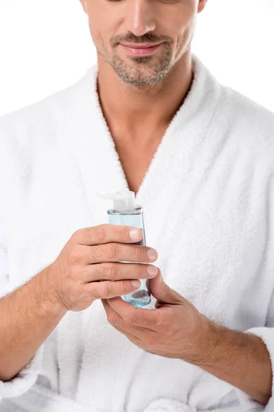 Vista parcial del hombre adulto en albornoz celebración loción de afeitar aislado en blanco - foto de stock