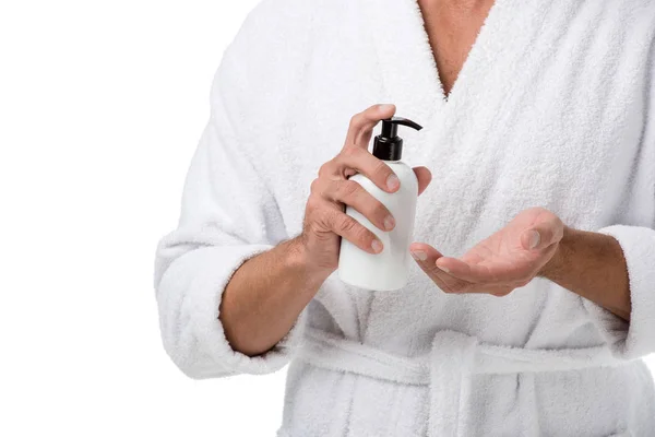 Imagem cortada do homem em roupão de banho usando loção corporal isolada em branco — Fotografia de Stock