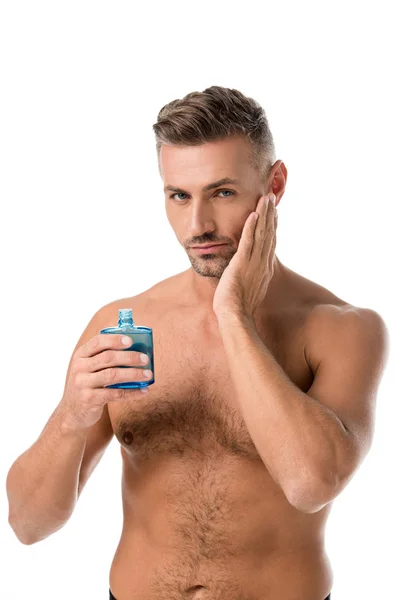 Confident shirtless muscular man using shaving lotion isolated on white — Stock Photo