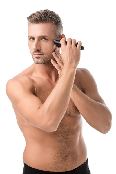 Serious adult man shaving with electric trimmer isolated on white — Stock Photo