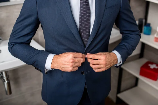 Cropped image of businessman buttoning up suit jacket in bathroom at home — Stock Photo