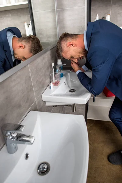 High angle view of businessman washing face over sink in bathroom — Stock Photo
