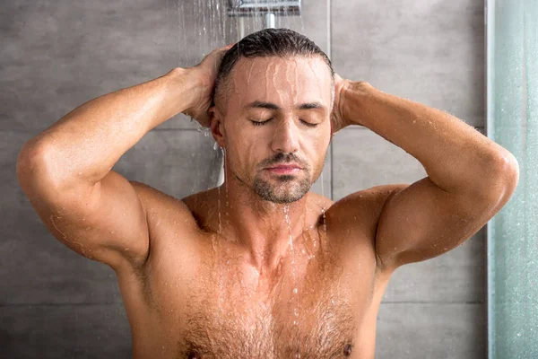 Portrait of adult man with closed eyes taking shower in morning — Stock Photo