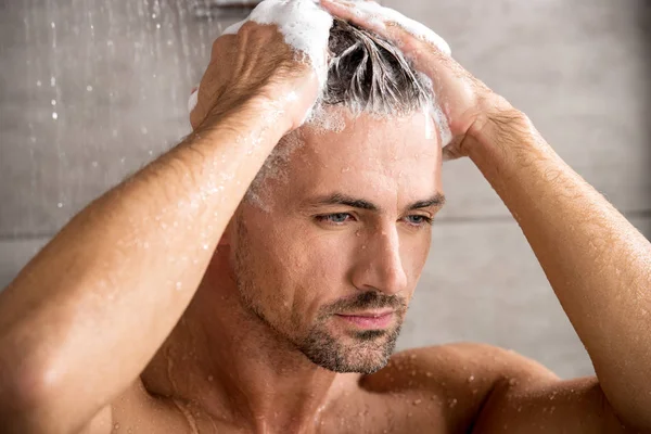 Close up portrait of adult man washing hair with shampoo and taking shower — Stock Photo