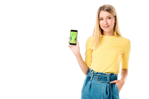 Schöne junge Frau hält Smartphone mit Einkaufsanwendung auf dem Bildschirm und lächelt in Kamera isoliert auf weiß — Stockfoto