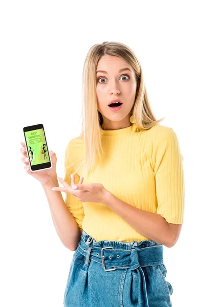 Shocked young woman holding smartphone with shopping application on screen and looking at camera isolated on white — Stock Photo