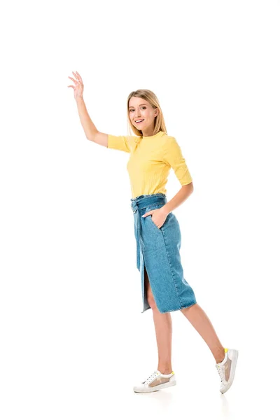 Full length view of smiling young woman waving hand and smiling at camera isolated on white — Stock Photo