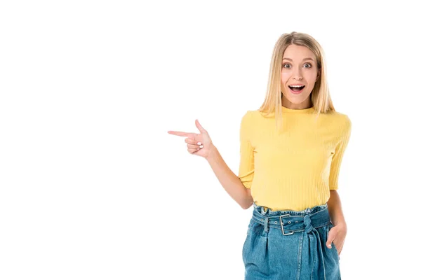 Sorprendida joven apuntando con el dedo y sonriendo a la cámara aislada en blanco — Stock Photo