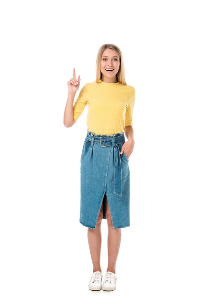 Atractiva joven apuntando hacia arriba con el dedo y sonriendo a la cámara aislada en blanco - foto de stock