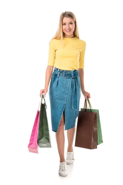 Full length view of beautiful young woman holding shopping bags and smiling at camera isolated on white — Stock Photo