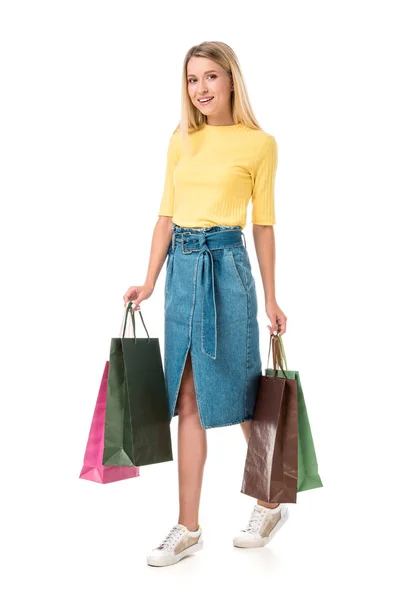 Vue pleine longueur de la jeune femme souriante tenant des sacs à provisions isolés sur blanc — Photo de stock