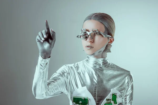 Futuristic silver cyborg gesturing with hand and looking away isolated on grey, future technology concept — Stock Photo
