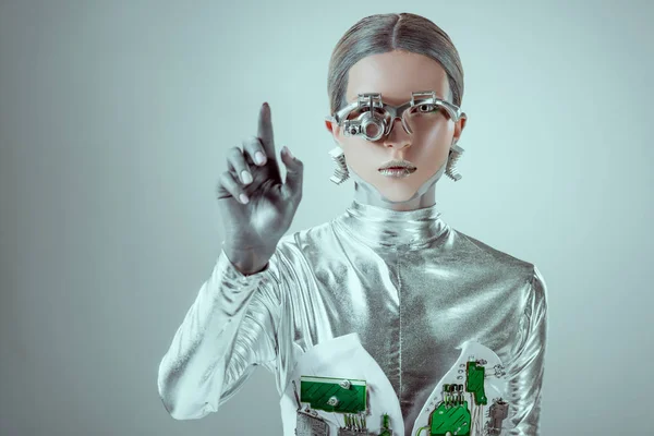 Футуристический серебряный киборг жестикулирующий рукой и смотрящий на камеру изолированную на серой, будущей технологической концепции — стоковое фото