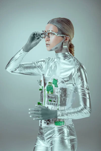 Futurista prata cyborg ajustando prótese ocular e olhando para longe isolado em cinza, conceito de tecnologia futuro — Fotografia de Stock