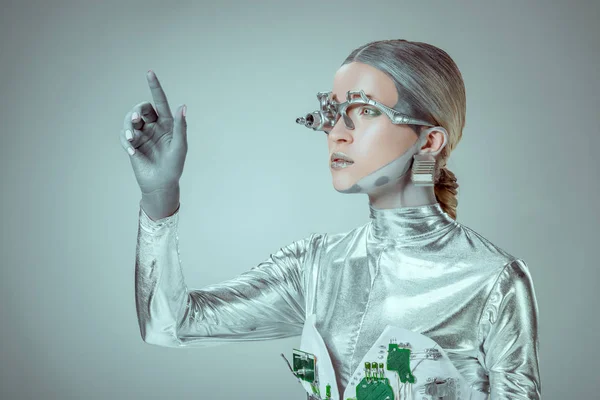 Futuristico robot d'argento gesticolare con mano e distogliere lo sguardo isolato sul grigio, concetto di tecnologia futura — Foto stock