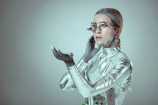 Futurista cyborg plata gesto con la mano y mirando hacia otro lado aislado en gris, el concepto de la tecnología del futuro - foto de stock