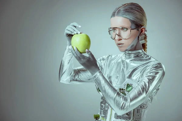 Robot in futuristic eyeglasses holding green apple isolated on grey, future technology concept — Stock Photo