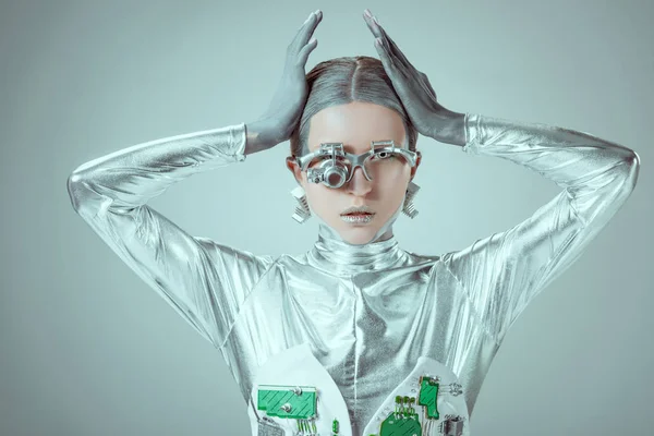 Молода жінка робот торкається голови і дивиться на камеру ізольовано на сірому, концепція майбутніх технологій — стокове фото