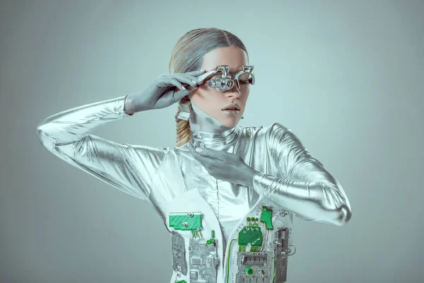 Молодая женщина-робот позирует в одиночестве на серой, технологической концепции будущего — стоковое фото