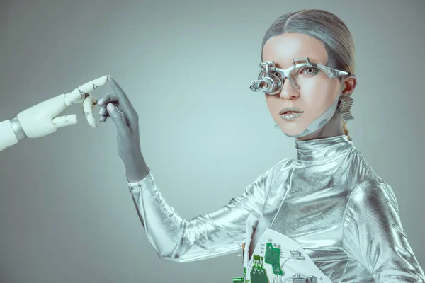 Cyborg tocando el brazo robótico y mirando a la cámara aislada en el concepto de tecnología gris y futura — Stock Photo