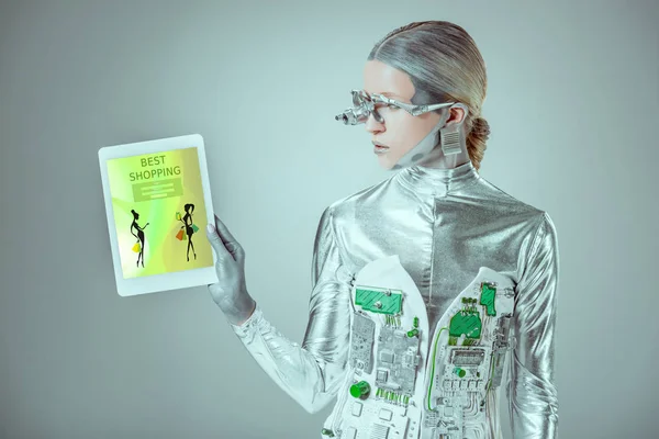 Robot d'argento guardando tablet con il miglior apparecchio di shopping isolato su grigio, concetto di tecnologia futura — Foto stock