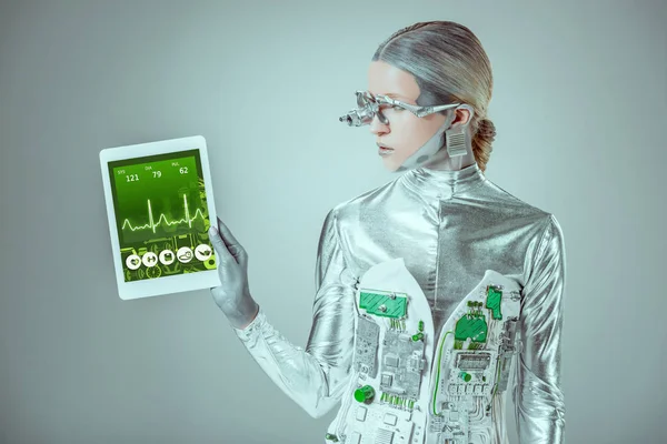 Срібний робот дивиться на планшет з медичним приладом ізольовано на сірому, концепція майбутніх технологій — стокове фото