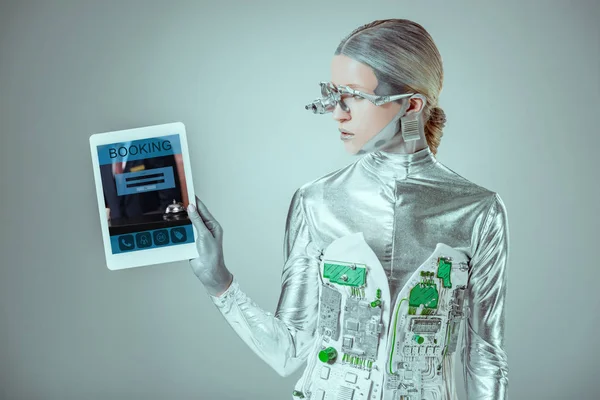 Silberroboter blickt auf Tablet mit Buchungsgerät isoliert auf graues, zukünftiges Technologiekonzept — Stockfoto