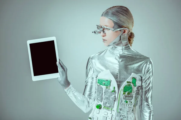 Серебряный робот держит планшет с чистым экраном, изолированным на сером, концепция технологии будущего — стоковое фото