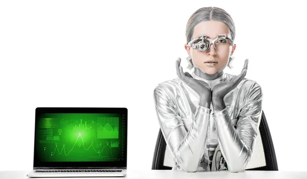 Срібний робот сидить за столом біля ноутбука з бізнес-приладом ізольовано на білому, концепція майбутніх технологій — Stock Photo