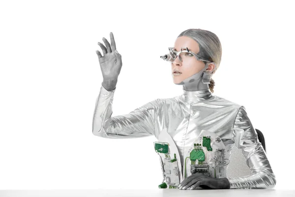 Silberroboter sitzt am Tisch und berührt etwas Isoliertes auf weißem, zukünftigem Technologiekonzept — Stockfoto