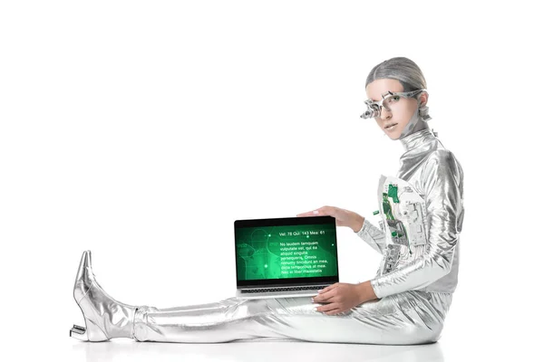 Robot plateado sentado y mostrando portátil con aparato médico aislado en blanco, concepto de tecnología futura - foto de stock