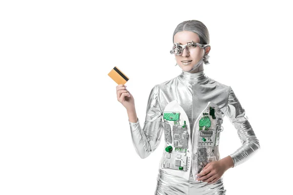 Robô de prata alegre segurando cartão de crédito e olhando para a câmera isolada em branco, conceito de tecnologia futuro — Fotografia de Stock