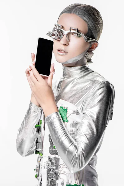 Silver robot holding smartphone with blank screen and looking at camera isolated on white, future technology concept — Stock Photo