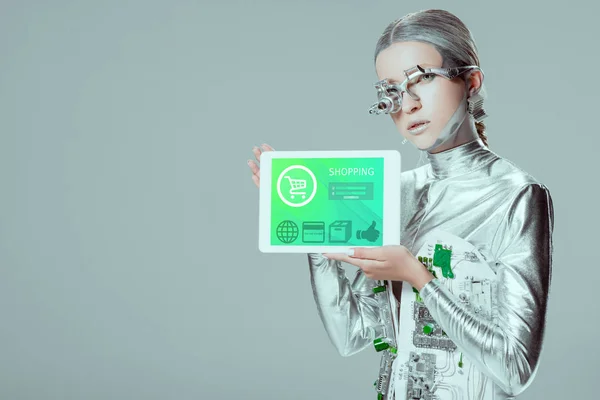 Robô de prata segurando tablet com aparelho de compras isolado no conceito de tecnologia cinza, futuro — Fotografia de Stock