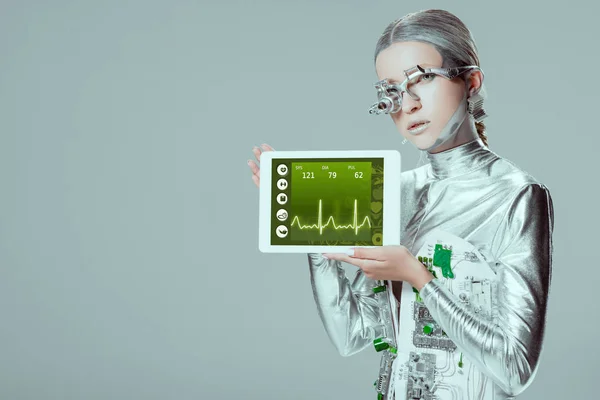 Срібний робот тримає планшет з медичним приладом ізольовано на сірому, концепція майбутніх технологій — стокове фото