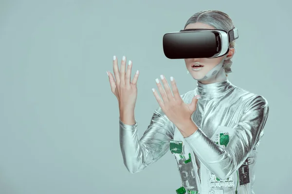 Robô de prata surpreendido olhando para as mãos com fone de ouvido realidade virtual isolado no conceito de tecnologia cinza, futuro — Fotografia de Stock