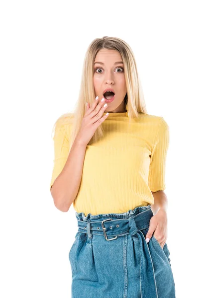 Scioccato donna attraente in camicia gialla gesticolando e guardando la fotocamera isolata su bianco — Foto stock