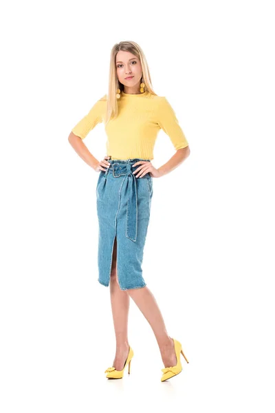 Mulher atraente confiante na camisa amarela de pé com as mãos akimbo e olhando para a câmera isolada no branco — Fotografia de Stock