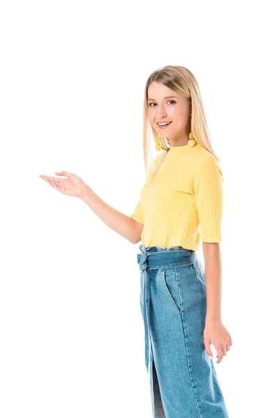 Smiling attractive woman in yellow shirt showing something and looking at camera isolated on white — Stock Photo