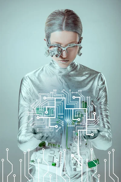Futuristischer silberner Cyborg blickt auf Leiterplatte isoliert auf graues, zukünftiges Technologiekonzept — Stockfoto
