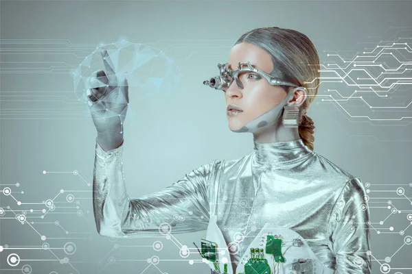 Futuristic silver cyborg gesturing with hand and looking at digital data isolated on grey, future technology concept — Stock Photo