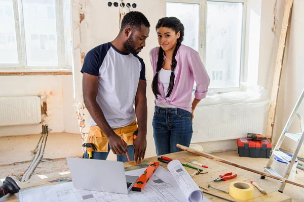 Pareja joven con herramientas y ordenador portátil haciendo renovación del hogar — Stock Photo